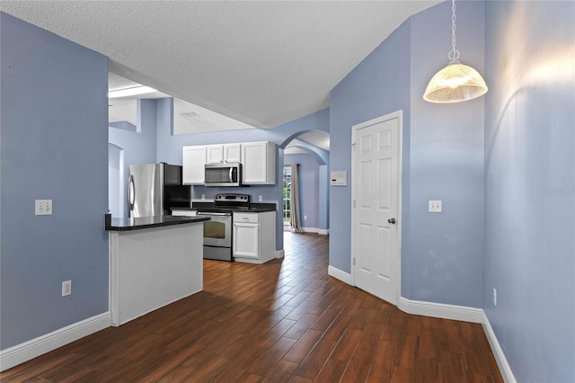 kitchen with stainless steel appliances, dark hardwood / wood-style floors, white cabinets, a textured ceiling, and decorative light fixtures