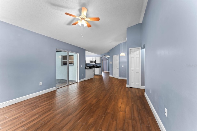 unfurnished living room with ceiling fan, lofted ceiling, dark hardwood / wood-style floors, and a textured ceiling