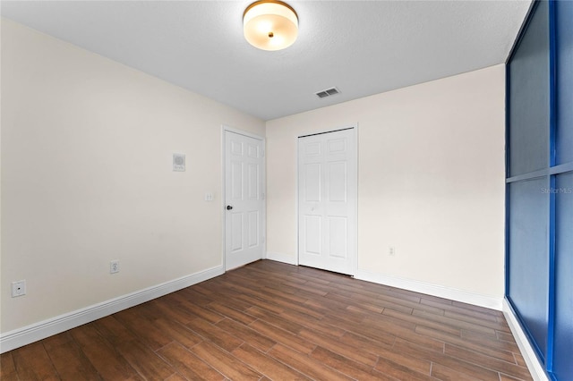 unfurnished bedroom featuring dark wood-type flooring and a closet