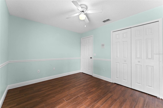 unfurnished bedroom with ceiling fan, dark hardwood / wood-style floors, a closet, and a textured ceiling