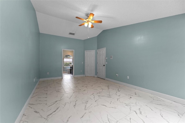 empty room with vaulted ceiling, a textured ceiling, and ceiling fan