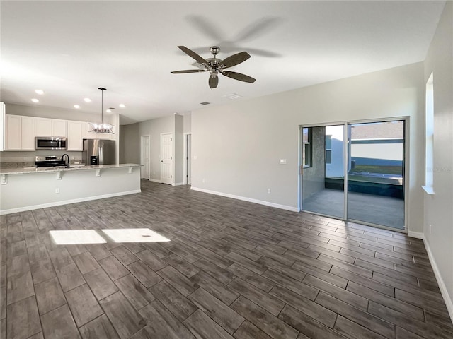 unfurnished living room with ceiling fan with notable chandelier