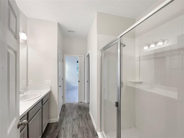 bathroom featuring a shower with shower door, vanity, a textured ceiling, and hardwood / wood-style floors