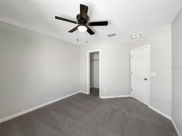 unfurnished bedroom featuring ceiling fan, a textured ceiling, and dark colored carpet