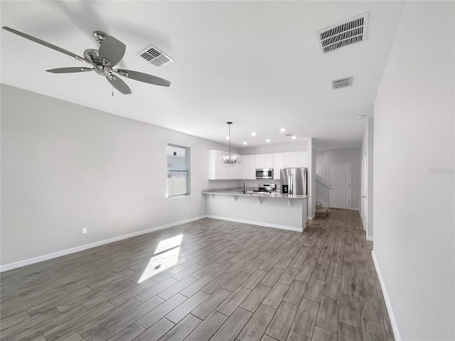 unfurnished living room with ceiling fan with notable chandelier and sink