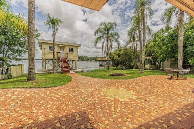 surrounding community with a patio, a water view, a storage unit, and a lawn