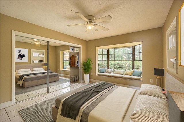 bedroom featuring ceiling fan, light tile patterned floors, and a textured ceiling