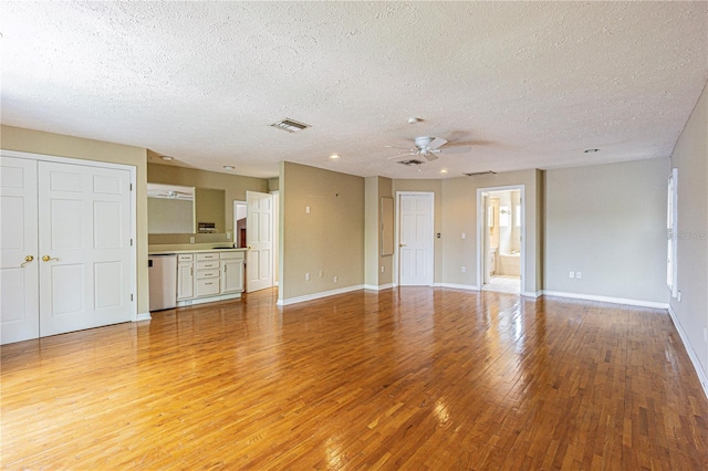 unfurnished living room featuring a textured ceiling, ceiling fan, and light wood-type flooring