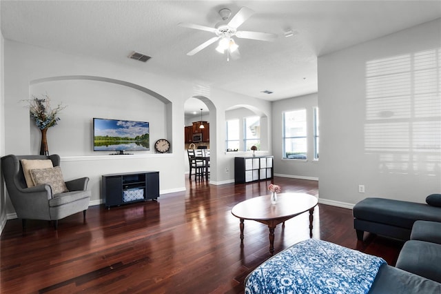 living room featuring ceiling fan, a textured ceiling, and dark hardwood / wood-style flooring