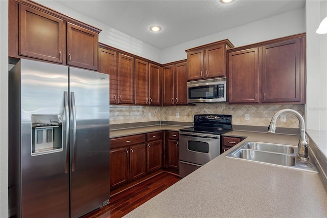 kitchen featuring sink, backsplash, dark wood-type flooring, and appliances with stainless steel finishes