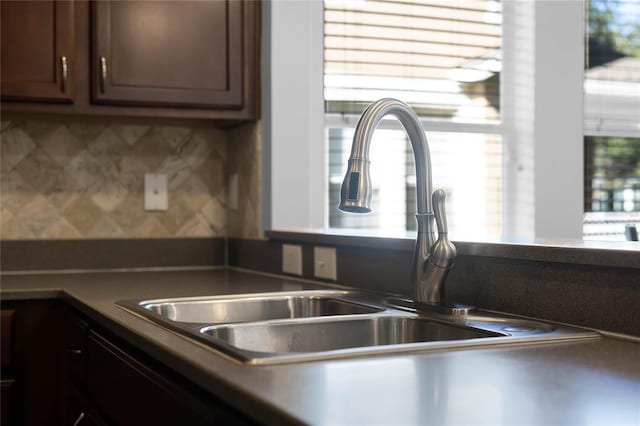 kitchen featuring sink, backsplash, and dark brown cabinets