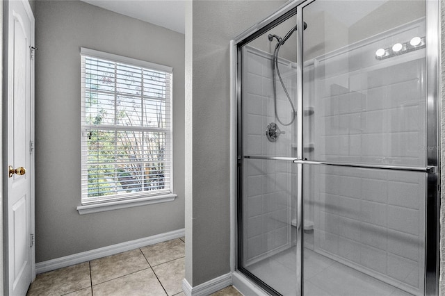 bathroom with a shower with door and tile patterned floors