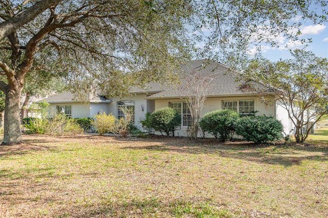 ranch-style house with a garage, stucco siding, a shingled roof, and a front lawn