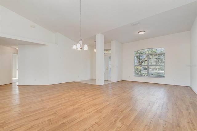 unfurnished living room with high vaulted ceiling, an inviting chandelier, and light hardwood / wood-style floors