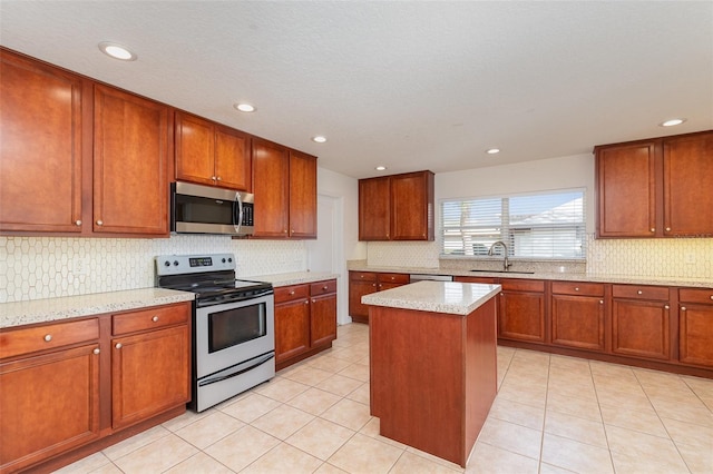 kitchen featuring sink, a kitchen island, stainless steel appliances, light stone counters, and light tile patterned flooring