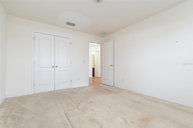 unfurnished bedroom with a closet and light carpet