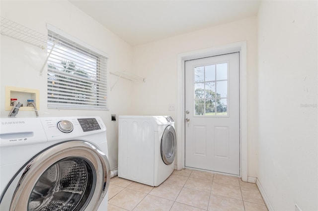 laundry room with washing machine and clothes dryer, laundry area, a healthy amount of sunlight, and light tile patterned floors