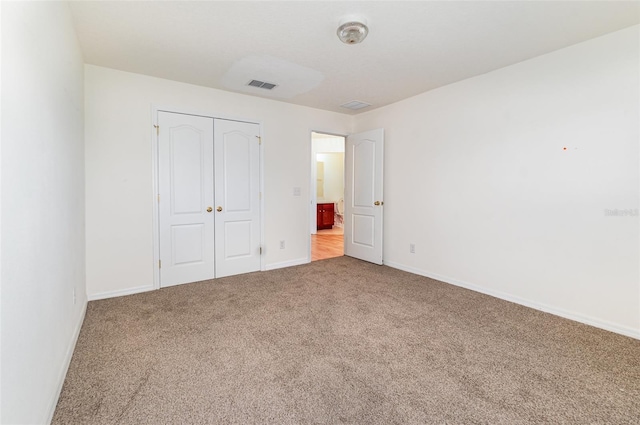 unfurnished bedroom featuring visible vents, carpet floors, baseboards, and a closet