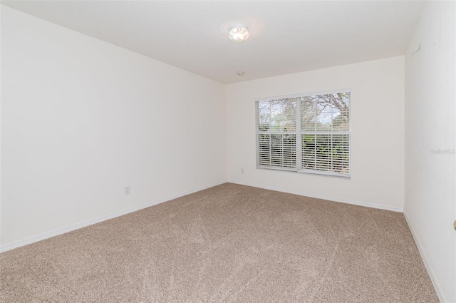 carpeted empty room featuring baseboards