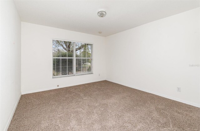 carpeted empty room featuring baseboards