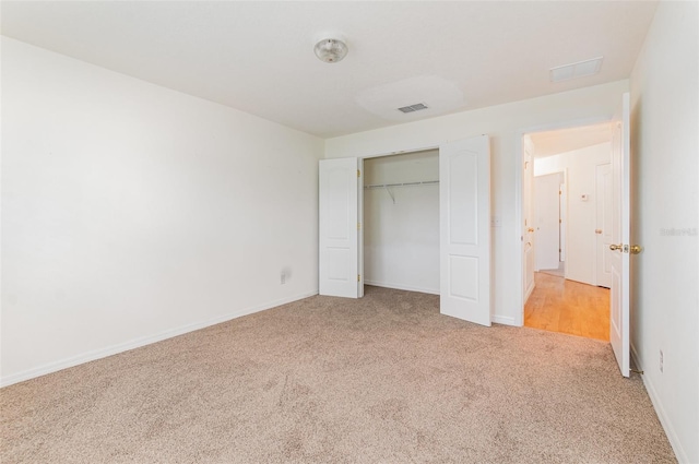 unfurnished bedroom featuring baseboards, visible vents, a closet, and light carpet