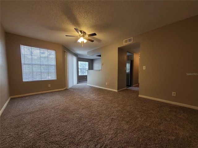 carpeted spare room with a textured ceiling and ceiling fan