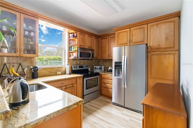 kitchen featuring light stone counters, backsplash, light hardwood / wood-style floors, and stainless steel appliances