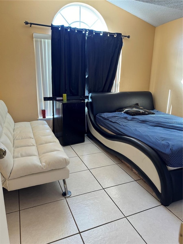 bedroom with lofted ceiling, tile patterned flooring, and a textured ceiling