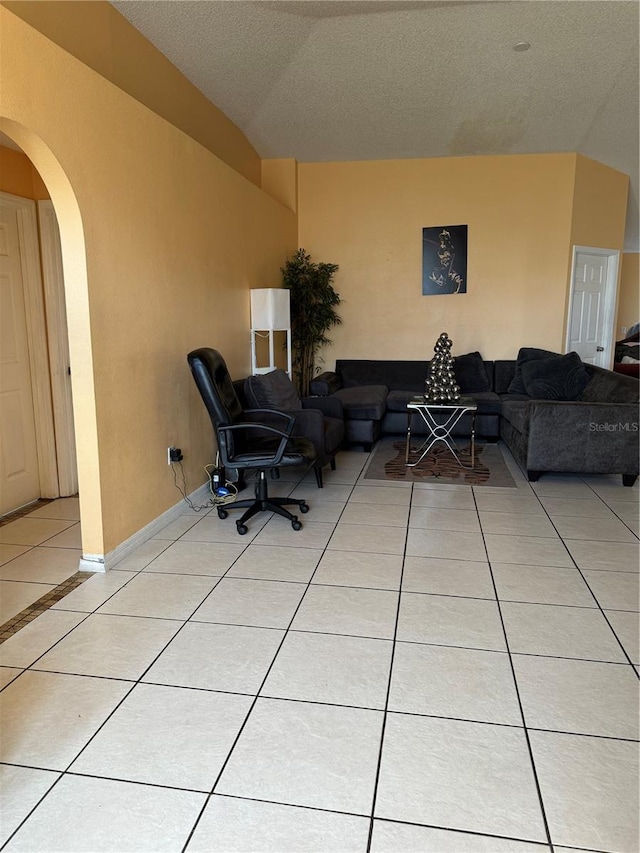 tiled living room featuring vaulted ceiling and a textured ceiling