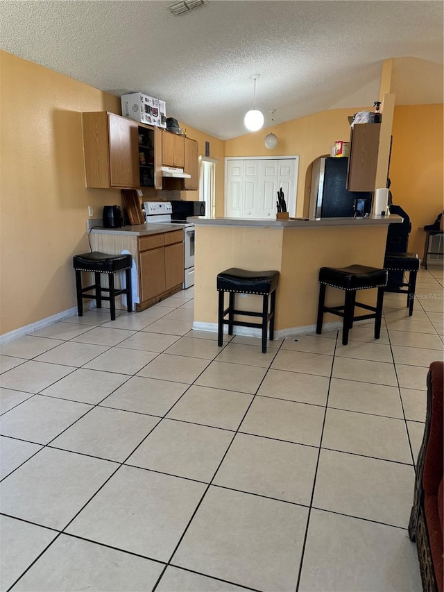 kitchen with white electric stove, a breakfast bar, stainless steel refrigerator, and kitchen peninsula