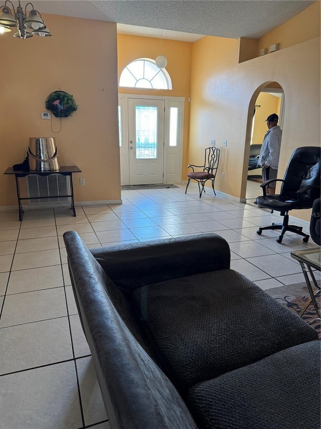 foyer entrance with light tile patterned flooring, an inviting chandelier, and a textured ceiling