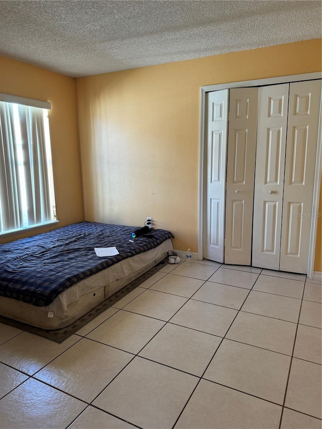 unfurnished bedroom with a closet, a textured ceiling, and light tile patterned flooring