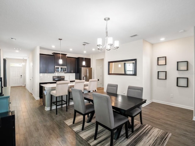 dining area with dark hardwood / wood-style floors and an inviting chandelier