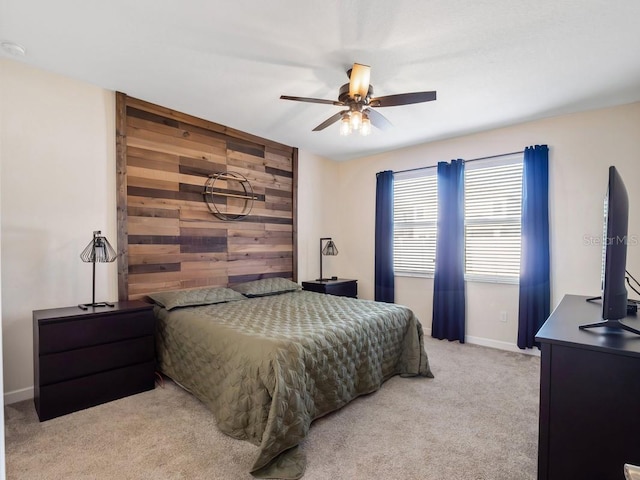 bedroom featuring ceiling fan, light carpet, and wooden walls