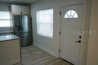 kitchen featuring baseboards, light wood-style flooring, light countertops, white cabinetry, and stainless steel refrigerator with ice dispenser