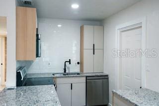 kitchen with white cabinets, stove, light stone countertops, stainless steel dishwasher, and a sink