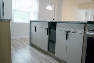 interior space with baseboards, light stone countertops, white cabinets, and light wood-style floors