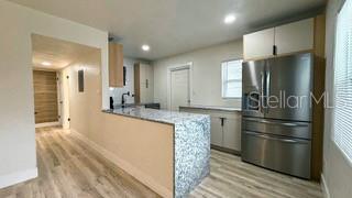 kitchen featuring a peninsula, light wood finished floors, white cabinetry, and stainless steel refrigerator with ice dispenser