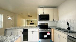 kitchen featuring white cabinets, ceiling fan, light stone counters, stainless steel appliances, and a sink