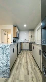 kitchen with white cabinets, light wood finished floors, stove, and light countertops