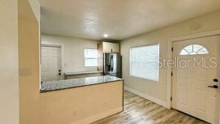 kitchen with baseboards, light countertops, freestanding refrigerator, and light wood-style floors