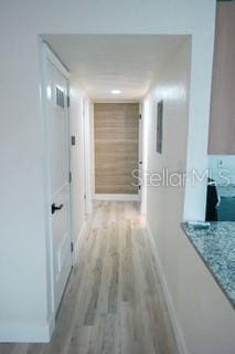 corridor with light wood-style floors and baseboards