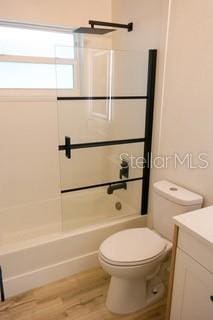 bathroom with toilet, shower / tub combination, wood finished floors, and vanity