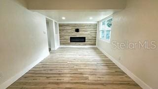 unfurnished living room featuring a glass covered fireplace, recessed lighting, baseboards, and wood finished floors