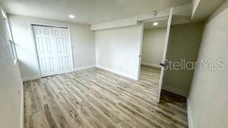 unfurnished bedroom with light wood-style flooring, baseboards, a closet, and recessed lighting