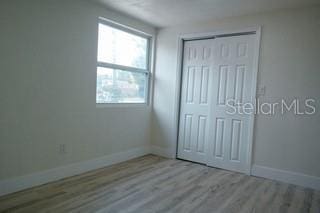 unfurnished bedroom with light wood finished floors, a closet, and baseboards