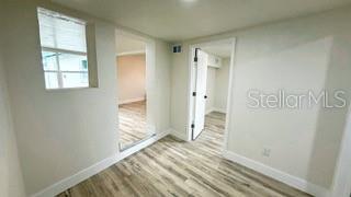 spare room featuring baseboards and light wood finished floors