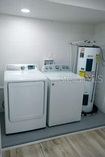 laundry area featuring electric water heater, recessed lighting, laundry area, separate washer and dryer, and light wood-style floors