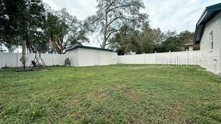 view of yard with a fenced backyard, a shed, and an outbuilding