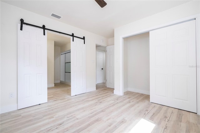 2002 Geigel Ave, Orlando, FL 32806 - unfurnished bedroom with a closet, a barn door, light wood-type flooring, visible vents, and baseboards